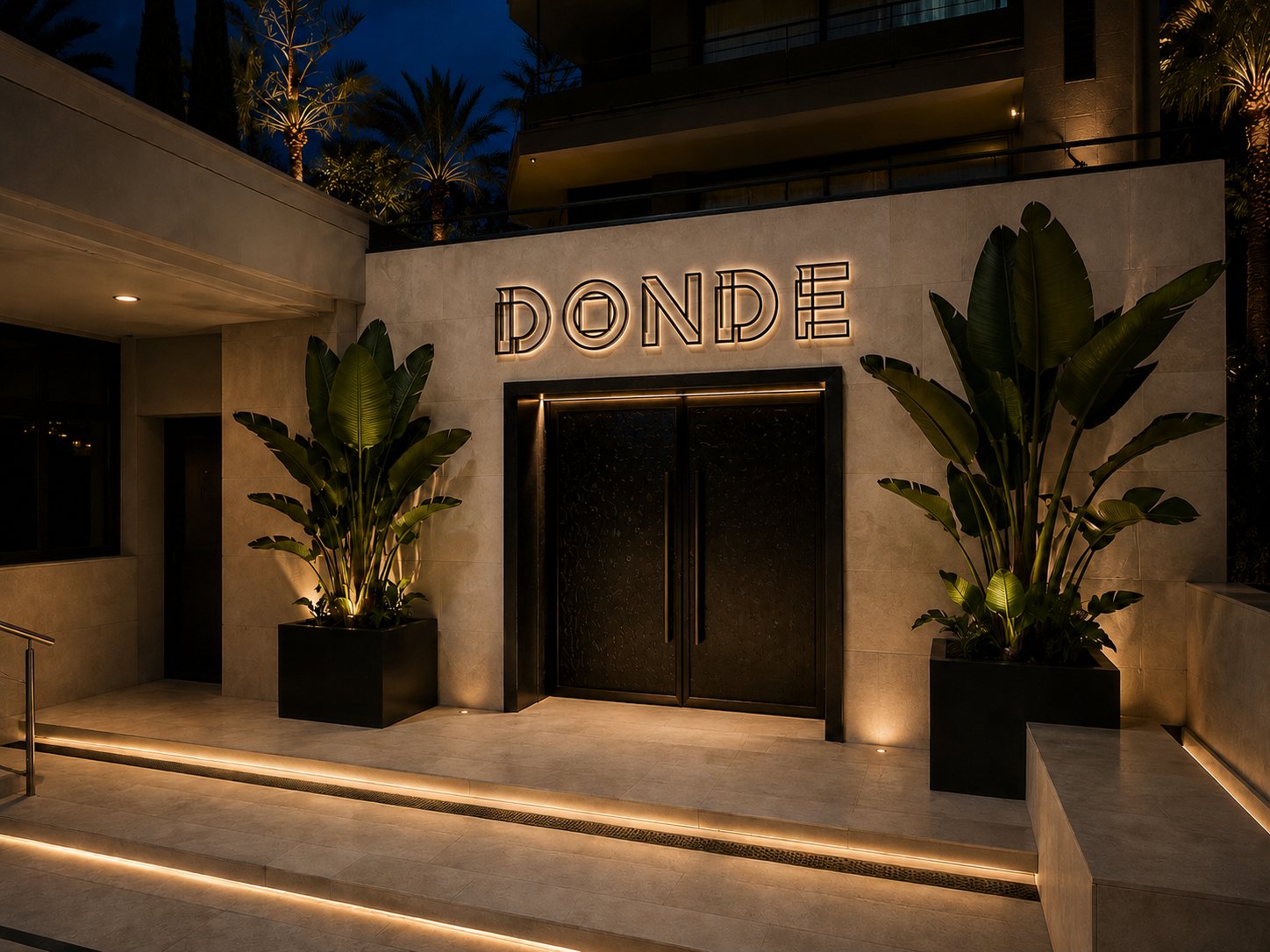 The DONDE entrance at dusk, travertine façade, dark double doors under the lit wordmark, palms and uplit steps